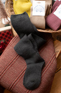 Black socks on a textured surface with a basket of other items in the background