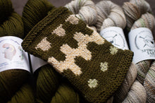 Load image into Gallery viewer, Knitted mitten with deer pattern surrounded by yarn balls and labels