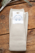 Load image into Gallery viewer, Folded beige sock with a label on a wooden surface
