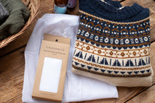 Load image into Gallery viewer, Patterned knitted item and COCOKNITS packaging on a wooden surface