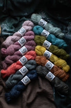 Load image into Gallery viewer, Assorted skeins of yarn in various colors arranged in a fan-like pattern on a dark fabric background.