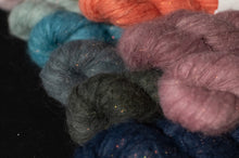 Load image into Gallery viewer, Close-up of various skeins of yarn in different colors on a dark background
