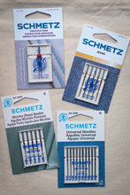 Load image into Gallery viewer, Four packages of Schmetz needles on a wooden surface