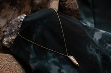Load image into Gallery viewer, Gold necklace with a pendant on a dark fabric background