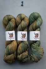 Load image into Gallery viewer, Three skeins of green and brown yarn with a brand label on a gray background