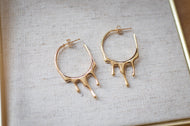 Gold hoop earrings on a textured gray surface
