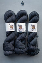 Load image into Gallery viewer, Three skeins of dark gray yarn with a label on a gray background