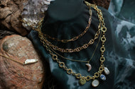Gold chain necklace with charms on a dark surface