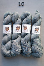 Load image into Gallery viewer, Four skeins of gray yarn with labels on a gray background
