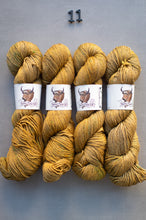 Load image into Gallery viewer, Four skeins of yellow yarn with labels on a gray background