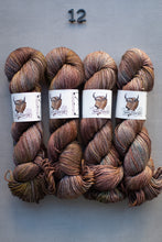 Load image into Gallery viewer, Four skeins of brown and red yarn with labels on a gray background