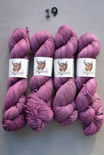 Load image into Gallery viewer, Four skeins of purple yarn with labels on a gray background