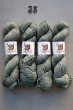 Load image into Gallery viewer, Four skeins of green yarn with labels on a gray background