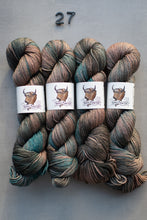 Load image into Gallery viewer, Four skeins of multicolored yarn with labels on a gray background