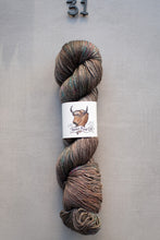 Load image into Gallery viewer, Skein of yarn with a label on a gray background