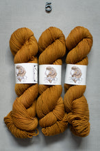 Load image into Gallery viewer, Three skeins of mustard yellow yarn with labels on a gray background