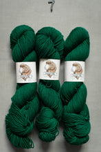 Load image into Gallery viewer, Three skeins of green yarn with labels on a gray background