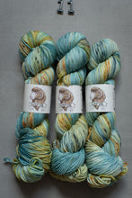 Load image into Gallery viewer, Three skeins of multicolored yarn with labels on a gray background