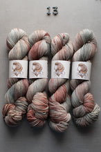 Load image into Gallery viewer, Four skeins of multicolored yarn with labels on a gray background