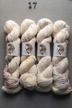 Load image into Gallery viewer, Set of four skeins of cream-colored yarn with speckles on a gray background