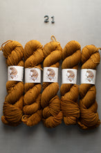 Load image into Gallery viewer, Five skeins of mustard yellow yarn with labels on a gray background