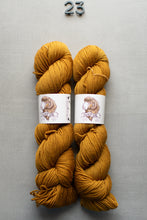 Load image into Gallery viewer, Two skeins of mustard yellow yarn with labels on a gray background