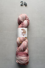 Load image into Gallery viewer, Multicolored skein of yarn with a label on a gray background