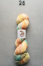 Load image into Gallery viewer, Multicolored skein of yarn with a label on a gray background