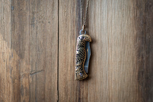 Eagle-shaped pendant on a chain against a wooden background