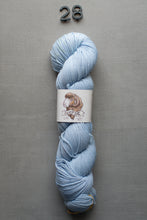 Load image into Gallery viewer, Light blue skein of yarn with a label on a gray background