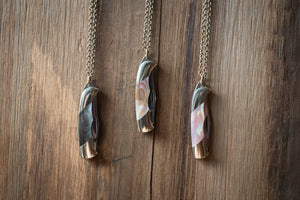Three necklaces with unique pendants on a wooden surface