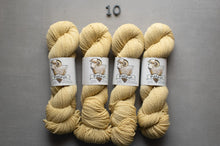 Load image into Gallery viewer, Four skeins of yellow yarn with labels on a gray background