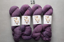Load image into Gallery viewer, Four skeins of purple yarn with labels on a gray background