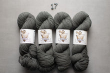 Load image into Gallery viewer, Four skeins of gray yarn with labels on a gray background