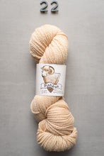 Load image into Gallery viewer, Beige skein of yarn with a label on a gray background