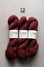 Load image into Gallery viewer, Three skeins of red yarn with labels on a gray background
