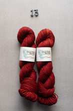 Load image into Gallery viewer, Two skeins of red yarn with labels on a gray background