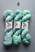 Load image into Gallery viewer, Three skeins of green yarn with speckles on a gray background