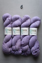 Load image into Gallery viewer, Four skeins of purple yarn with labels on a gray background