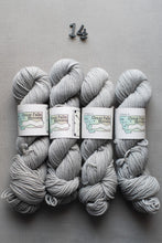 Load image into Gallery viewer, Gray yarn skeins with labels on a gray background