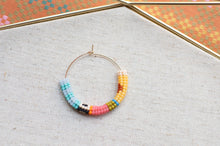 Load image into Gallery viewer, Colorful beaded hoop necklace on a textured surface with a patterned background