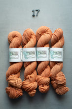 Load image into Gallery viewer, Four skeins of peach-colored yarn with labels on a gray background