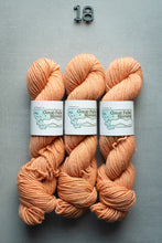 Load image into Gallery viewer, Three skeins of peach-colored yarn with labels on a gray background