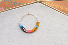 Load image into Gallery viewer, Colorful beaded hoop on a textured surface with a patterned background