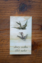 Load image into Gallery viewer, Silvery swallow stitch marker on a wooden surface with packaging