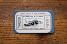 Load image into Gallery viewer, Stitch marker for tinned fish on a vintage-style card with blue border on wooden surface
