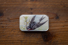 Load image into Gallery viewer, Small tin box with a bird illustration on a wooden surface