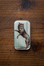Load image into Gallery viewer, Metallic tin with a wolf design on a wooden surface