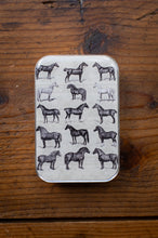Load image into Gallery viewer, Small tin box with illustrations of horses on a wooden surface