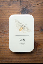 Load image into Gallery viewer, Rectangular white box with a butterfly illustration and 'Live Simply' text on a wooden surface